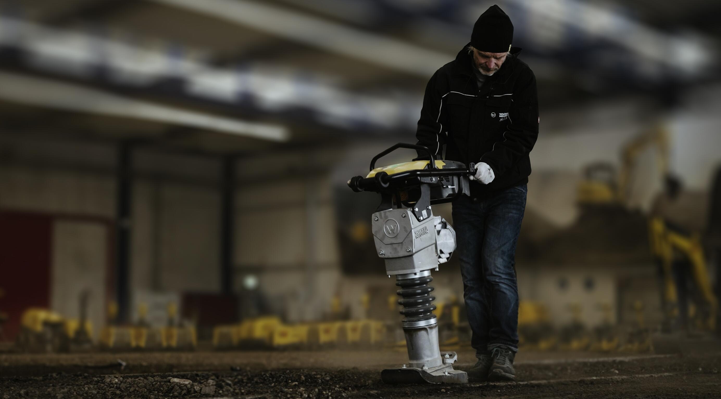 Operaio che utilizza un costipatore per la compattazione del terreno in un ambiente di formazione edile al chiuso