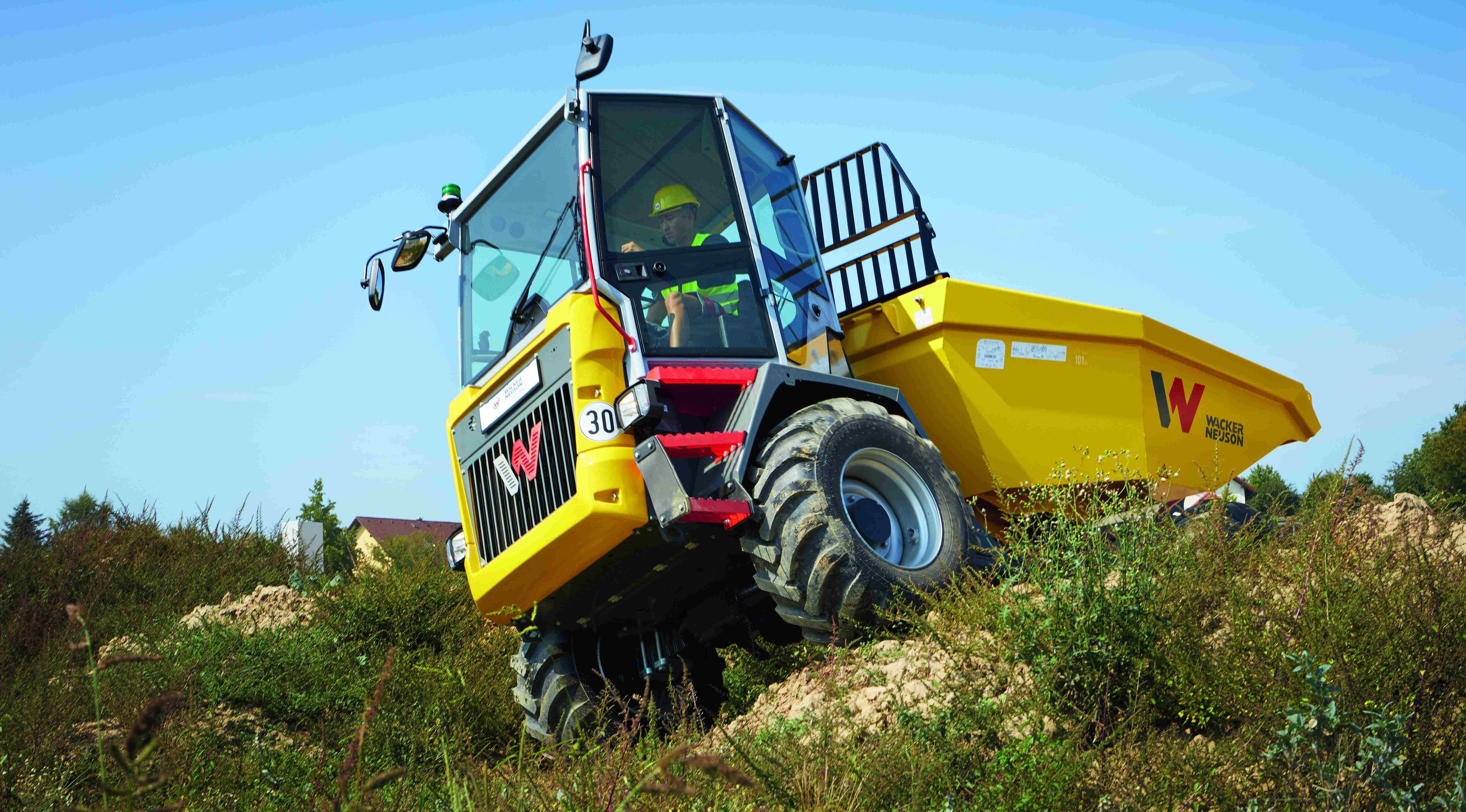 Dumper Wacker Neuson in marcia su terreno irregolare con l'operatore in cabina durante i lavori di costruzione
