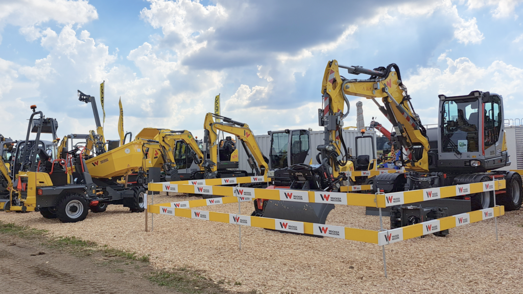 Yellow Wacker Neuson excavators and construction machines at a trade fair booth.