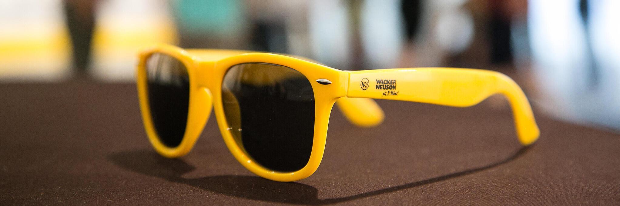 Des lunettes de soleil jaunes portant le logo Wacker Neuson.