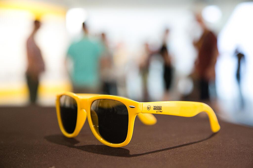 Gelbe Sonnenbrille mit Wacker Neuson Logo.