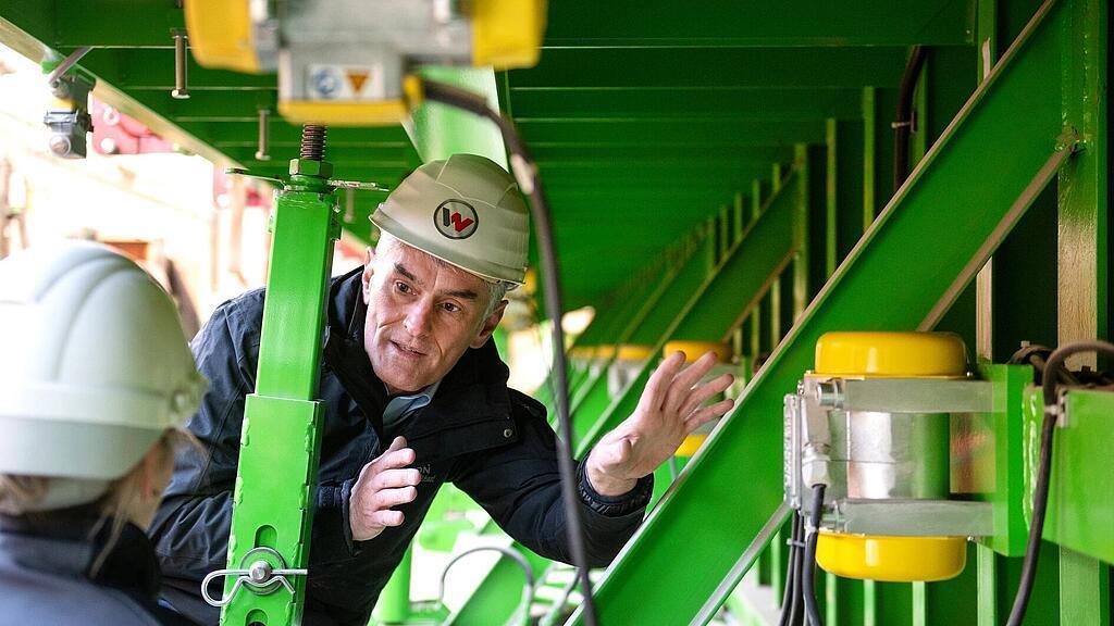 Il dipendente Wacker Neuson si trova davanti al vibratore esterno e lo spiega.