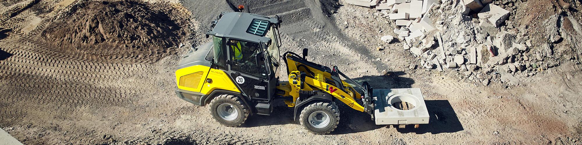 Ein Wacker Neuson WL750p-Performance-Radlader transportiert ein Element aus Beton auf einer Baustelle.